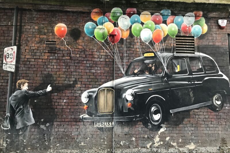 Glasgow painting on wall of Black Cab tied to balloons